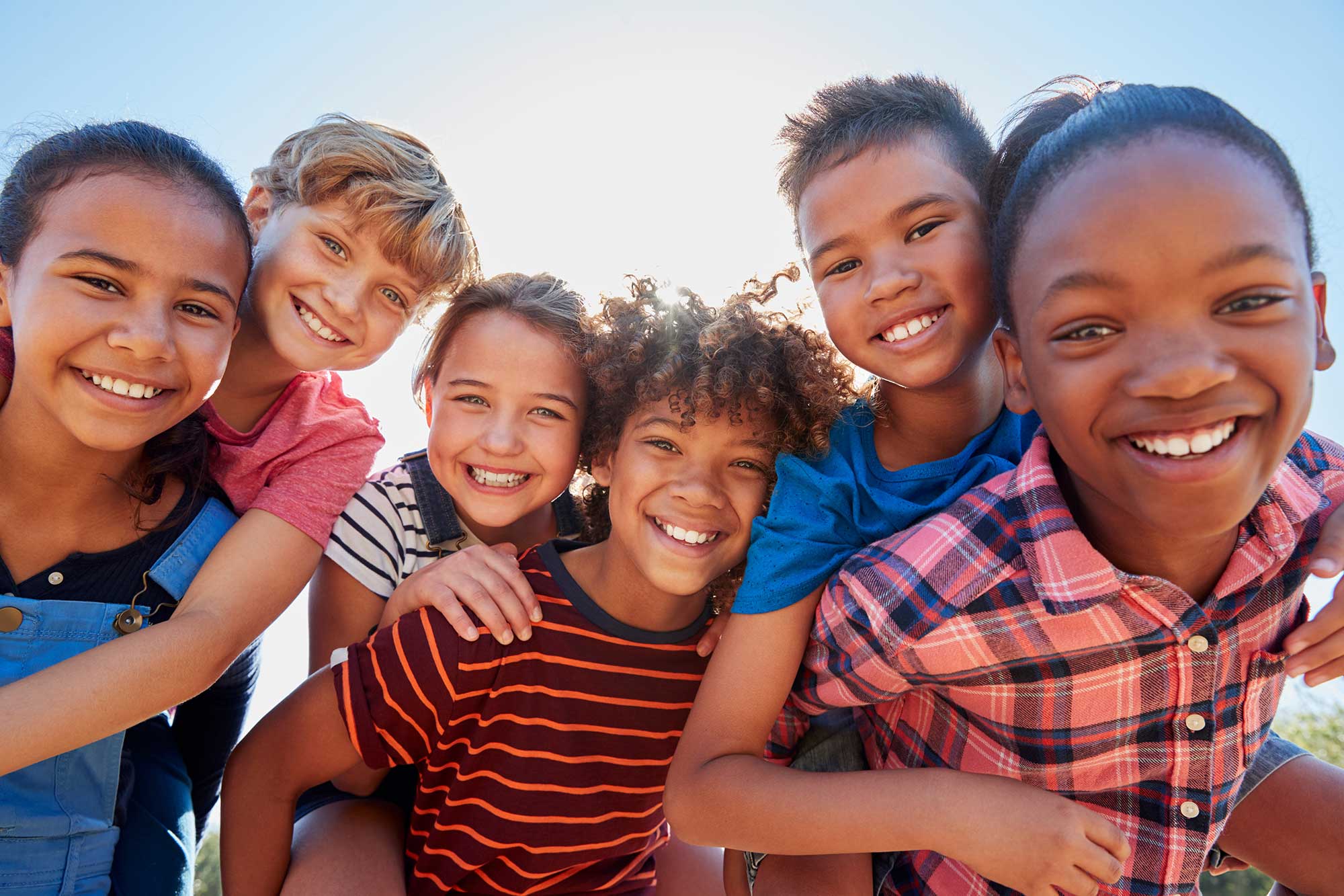 A group of kids huddled together, smiling for the camera.