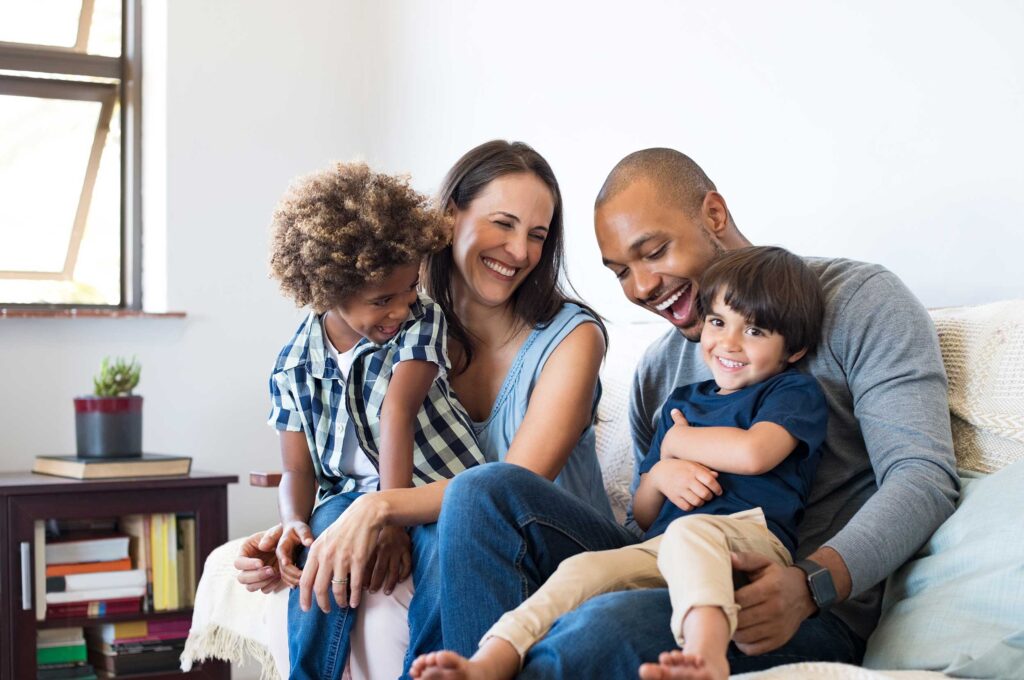 Smiling parents with their two happy children on the couch.