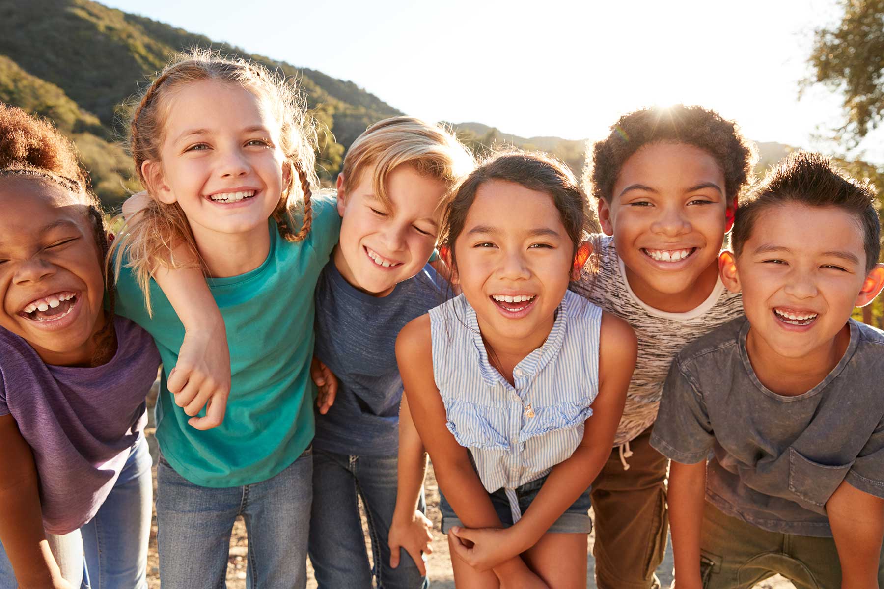 Group of children huddled together smiling.