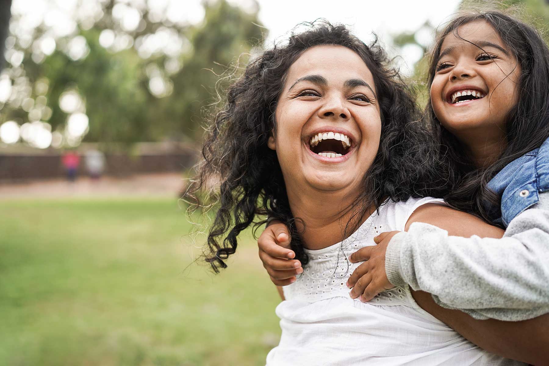 Laughing adult giving their child a piggy back ride.