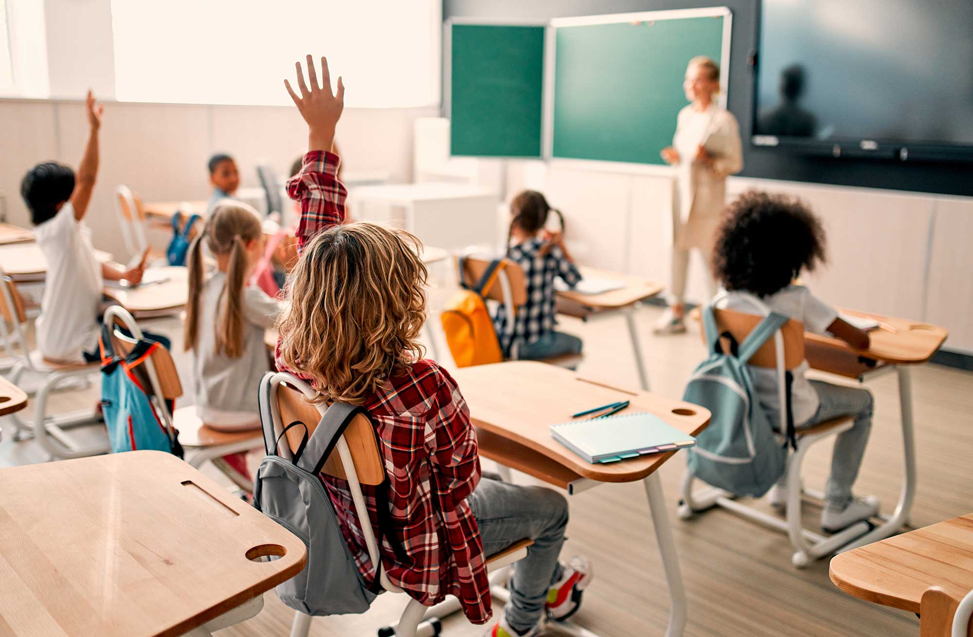 Group of students in a classroom with their hands raised.